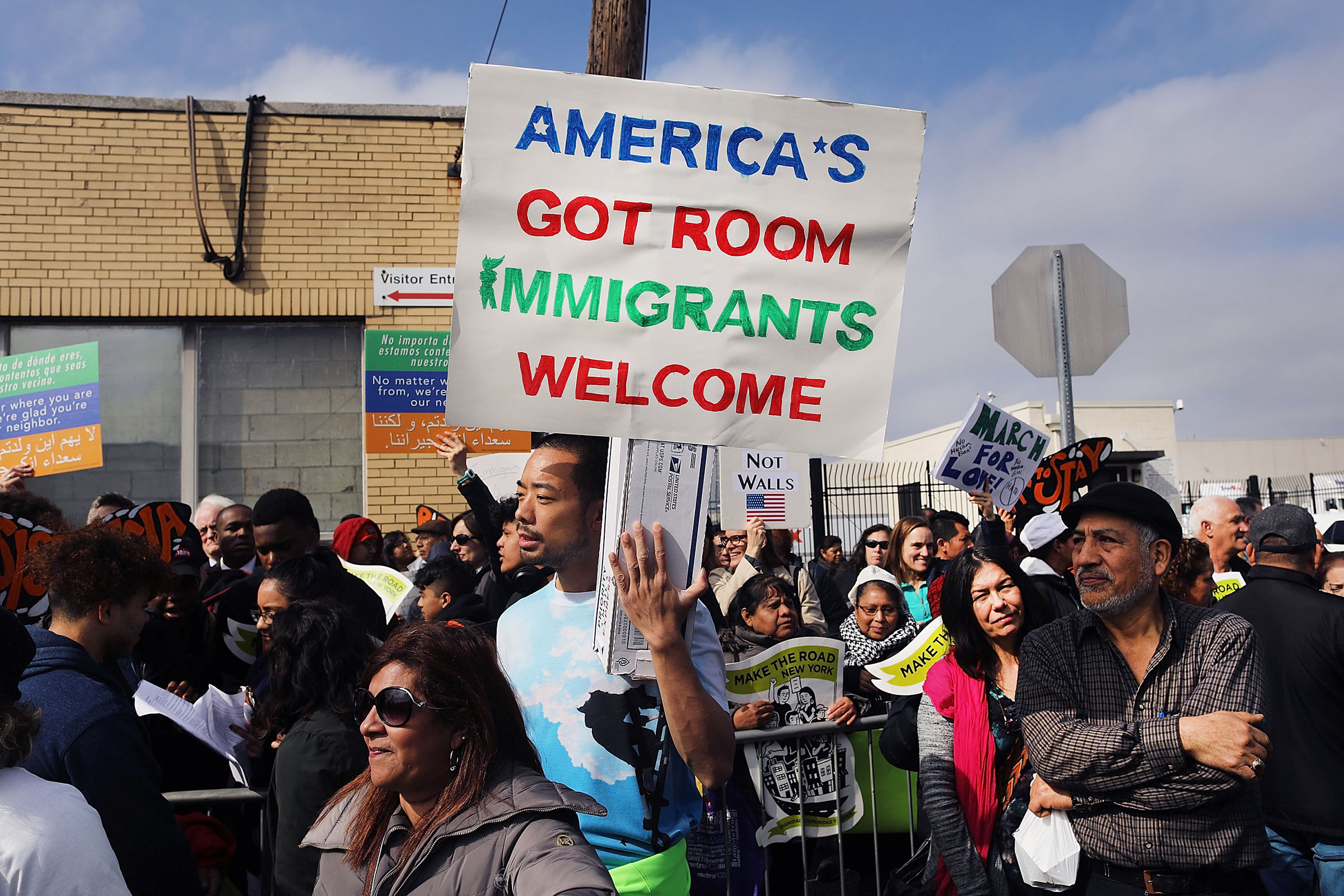 A man holds a sign reading "AMERICA'S GOT ROOM; IMMIGRANTS WELCOME" during an outdoor protest