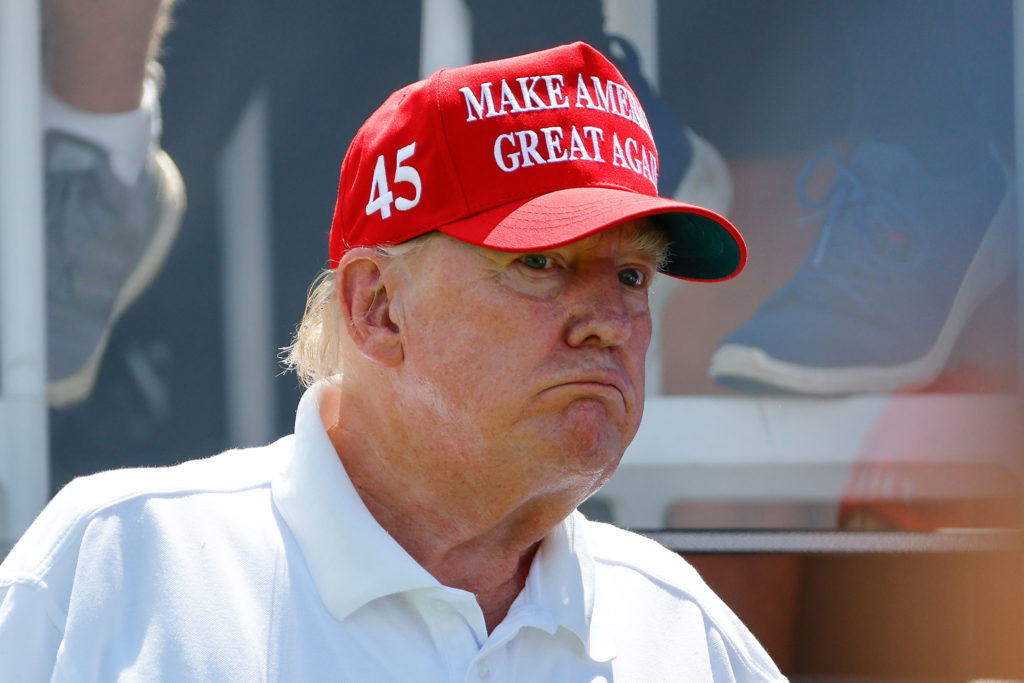 Donald Trump, wearing a Make America Great Again hat, looks bewildered by something occurring out of frame