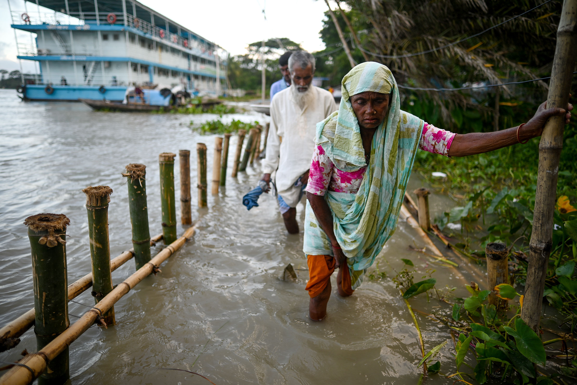 A woman walks through shin-deep floodwater, along with several others