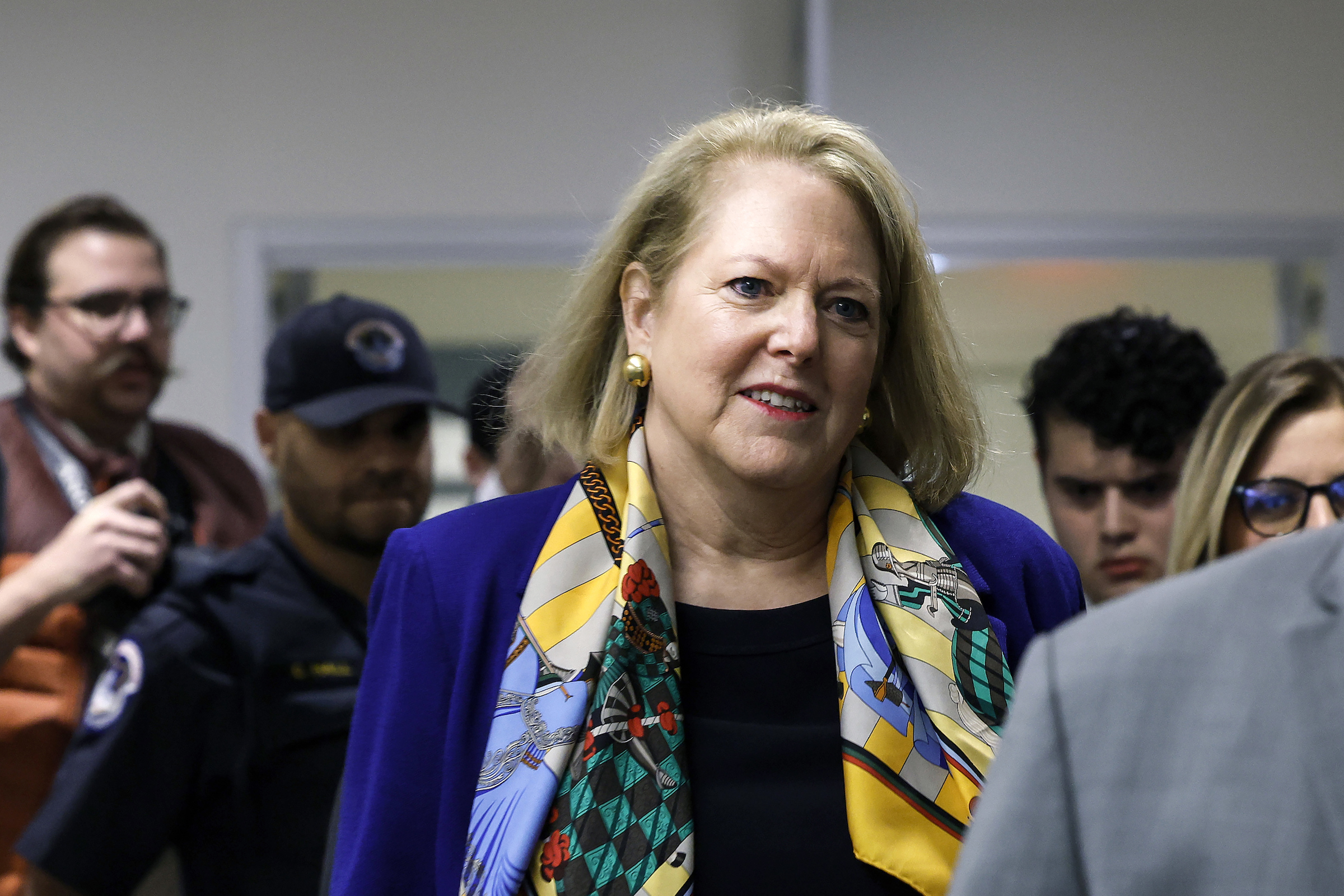 Ginni Thomas, a white woman with short blond hair walks in a crowd of people.