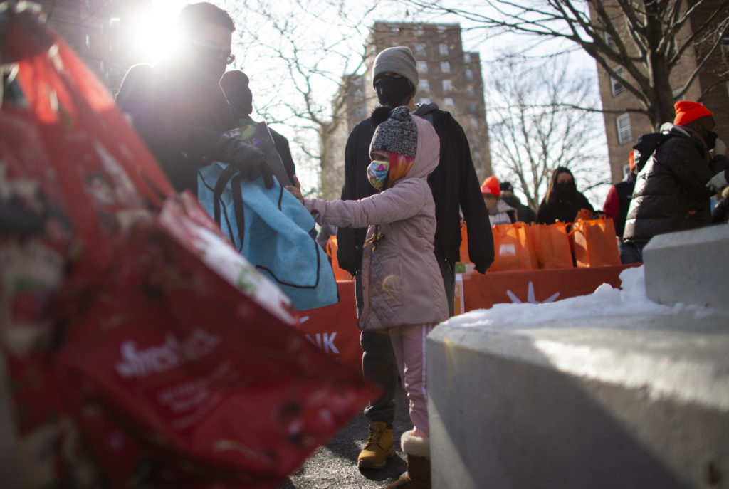 A girl receives a Christmas gift during a giveaway organized by Food Bank For New York City at Highbridge Houses in the Bronx on December 19, 2020, in New York City.