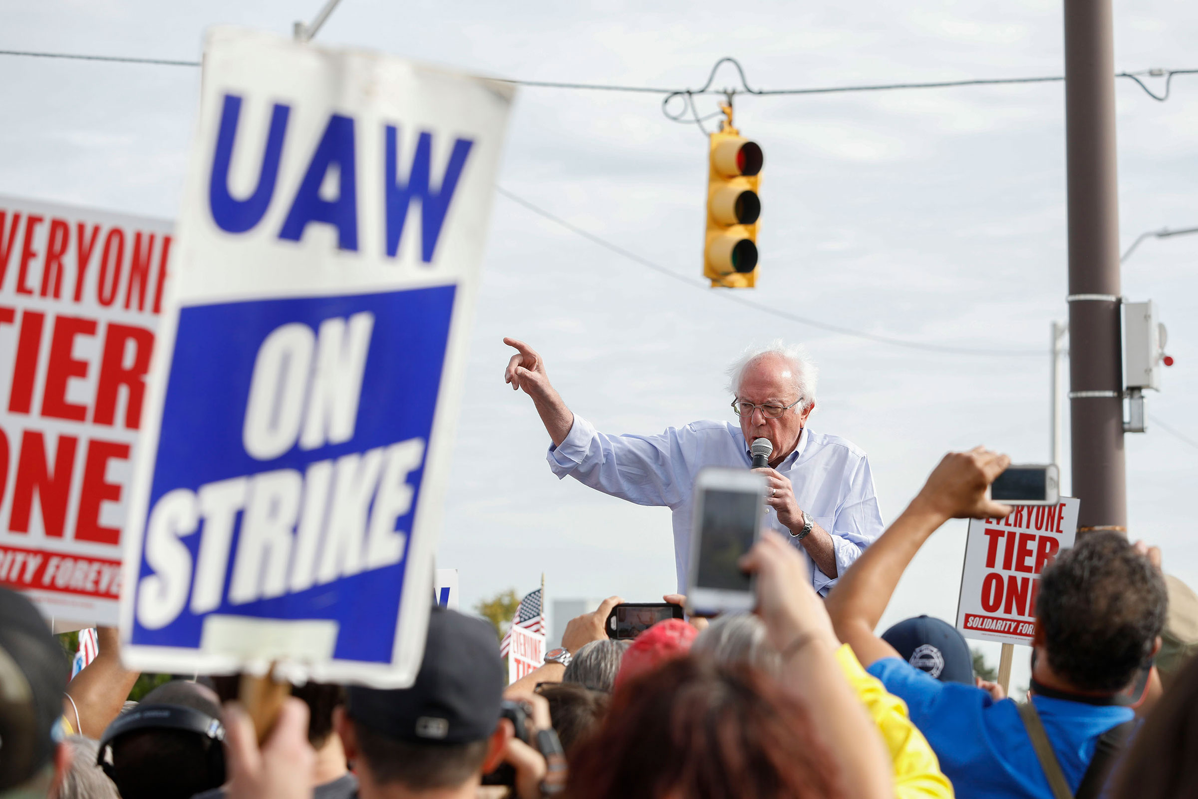 Bernie Sanders speaks passionately to rallying United Auto Worker members, one of whom are holding signs reading