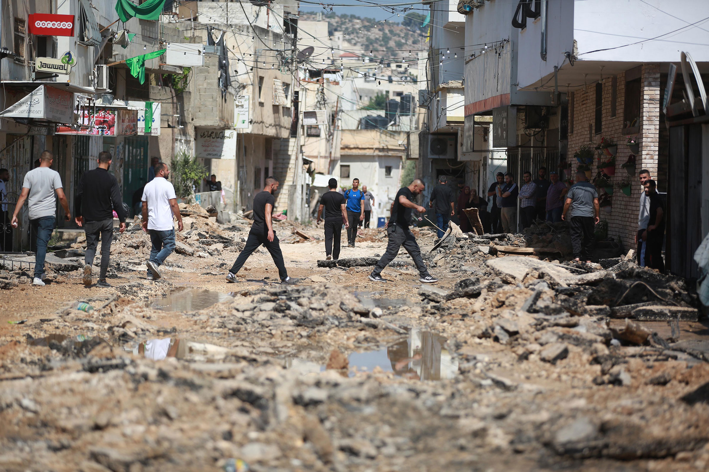 People walk through the rubble that was once a residential street