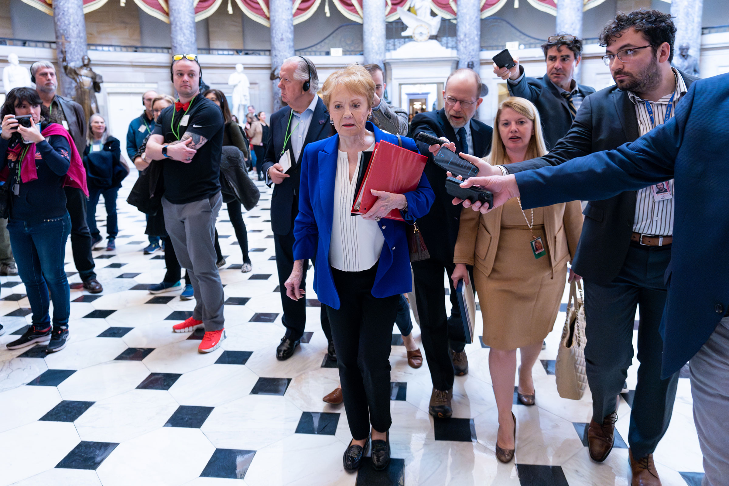 Rep. Kay Granger is interviewed by journalists holding out recording devices as she walks