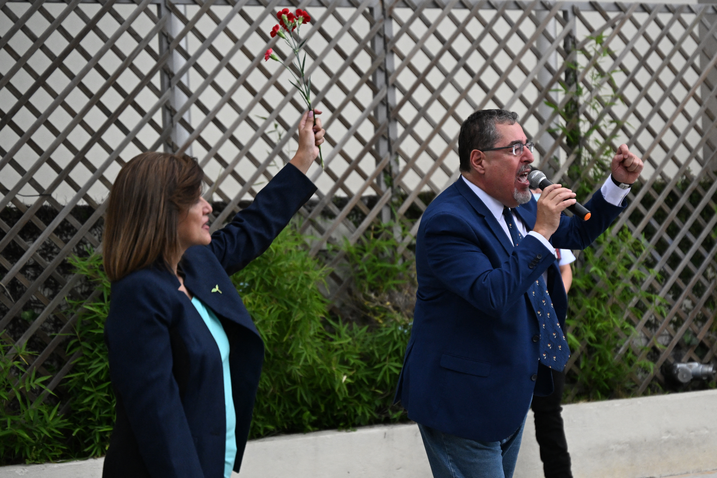 Guatemalan president-elect for the Movimiento Semilla party, Bernardo Arevalo (R), speaks to supporters next to his running mate, Karin Herrera, during a demonstration outside the Attorney General