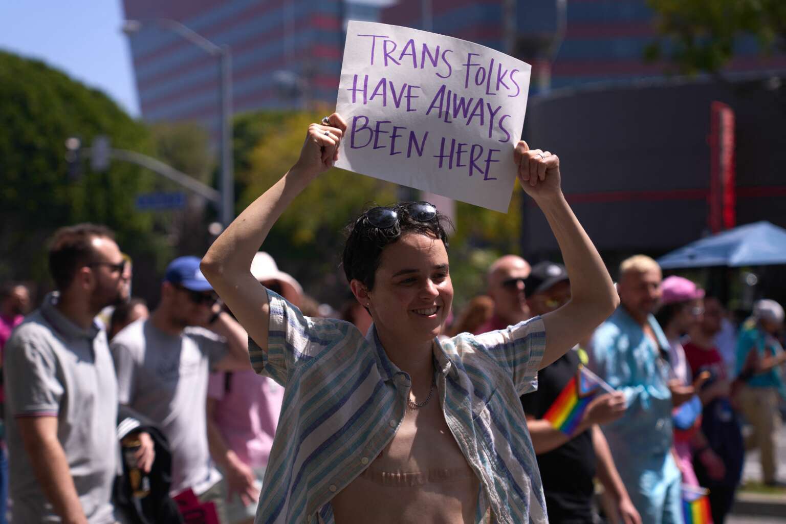A transgender person holds a sign reading "Trans Folks Have Always Been Here" as LGBTQ+ activists march during the Los Angeles LGBT Center