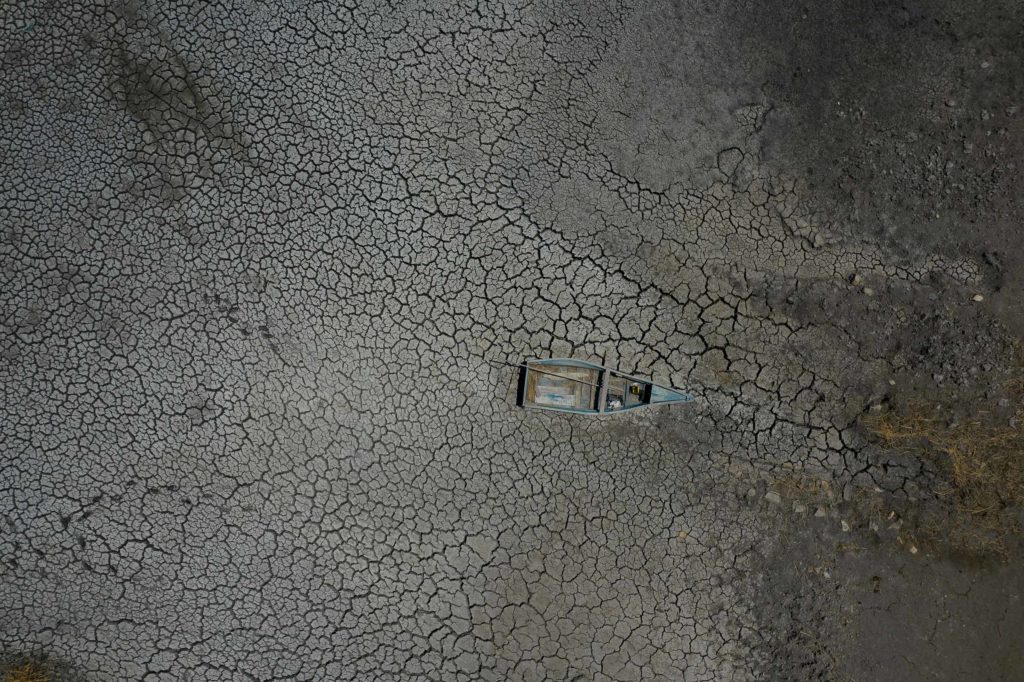 A boat lies abandoned on a dry lake bed