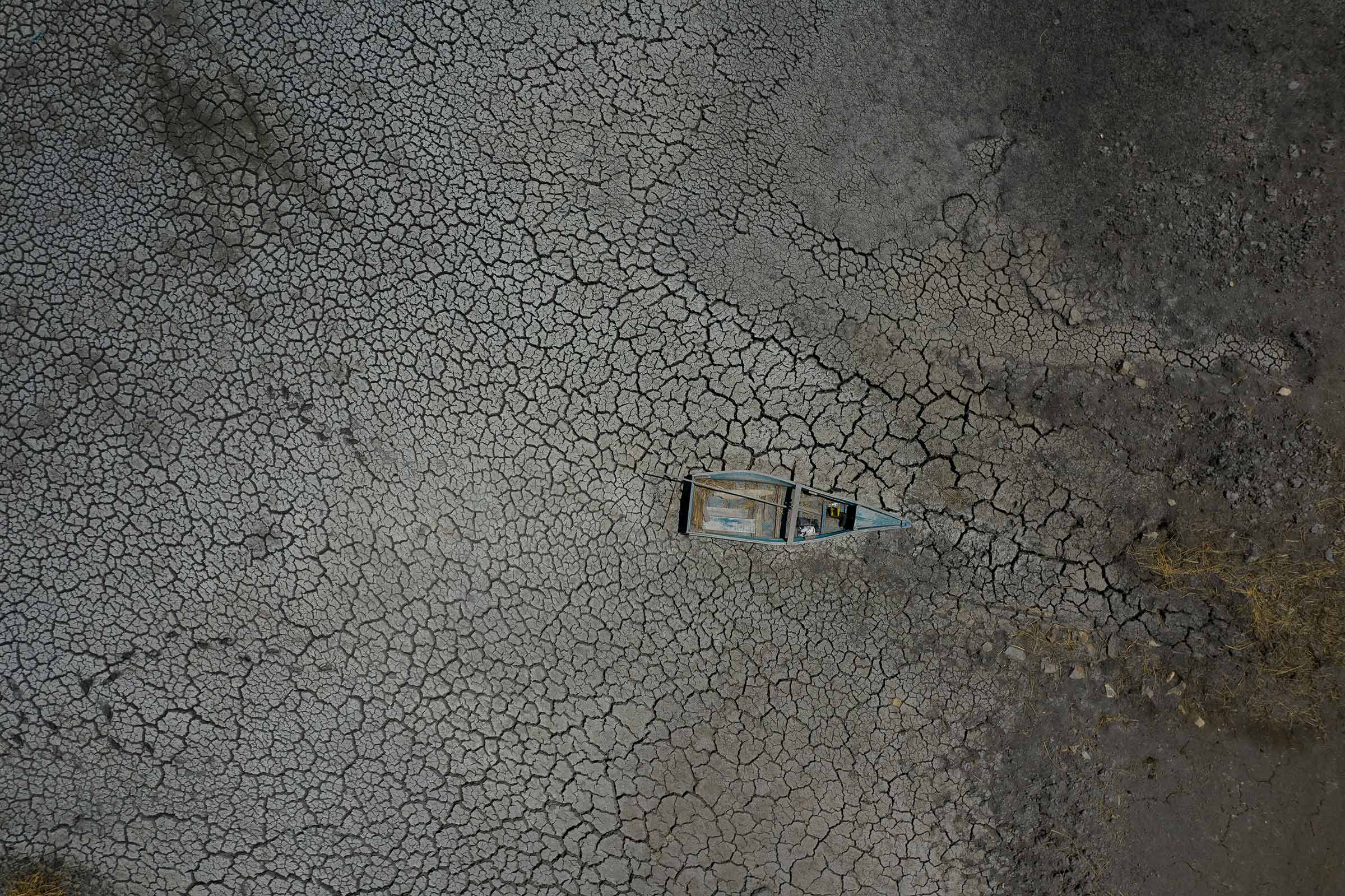 A boat lies abandoned on a dry lake bed