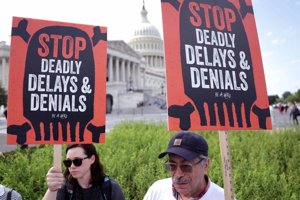 Two people hold signs reading