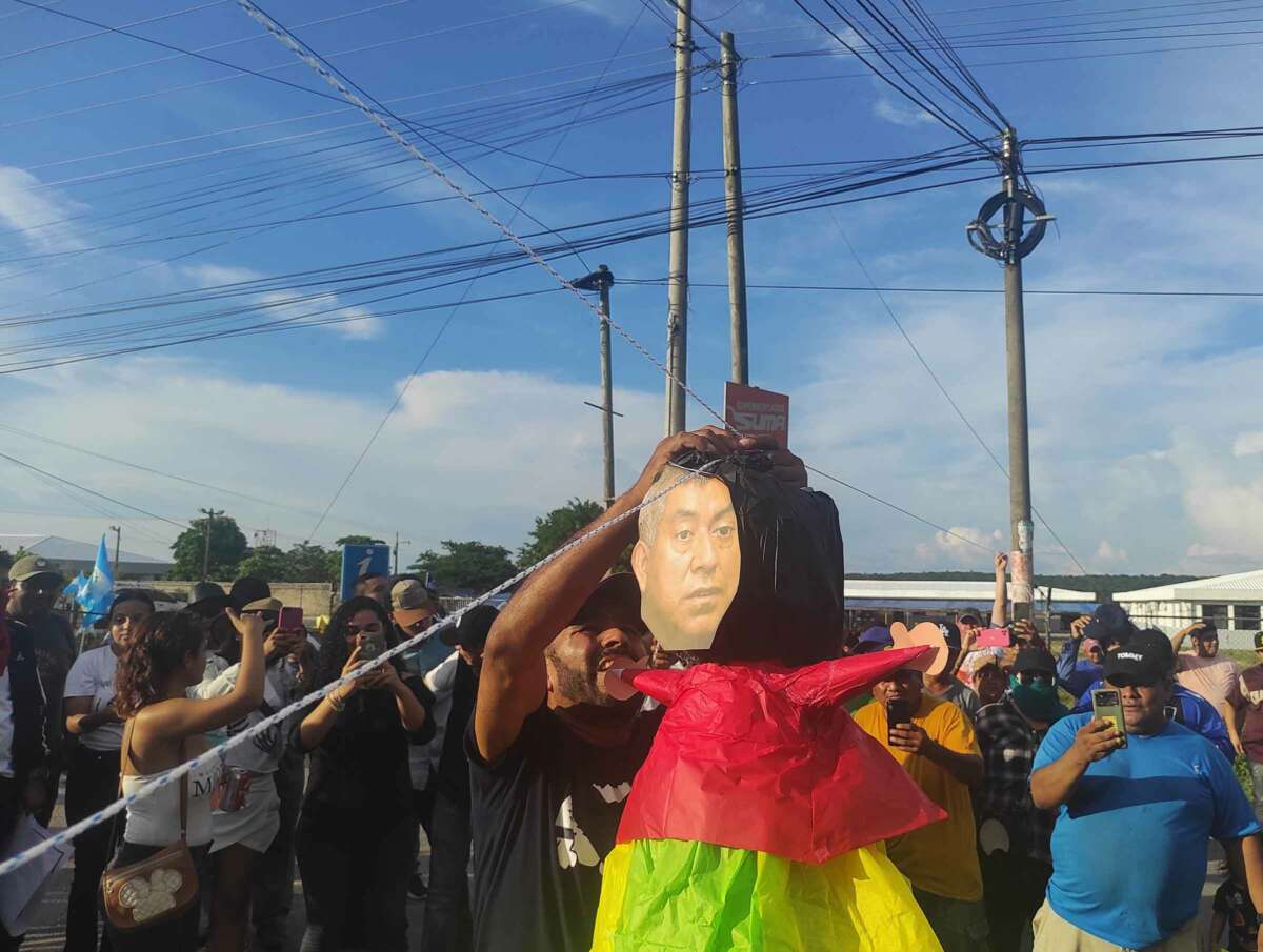 Lors d'un blocus à Santa Elena, Petén, un manifestant enfile une piñata représentant le visage du procureur spécial anti-impunité Rafael Curruchiche.