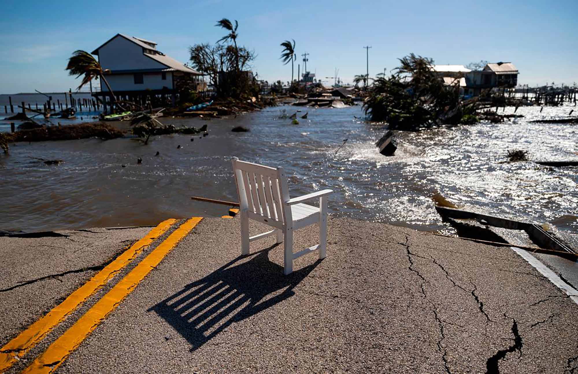 A lone lawn chair overlooks massive flooding of a street ahead of it