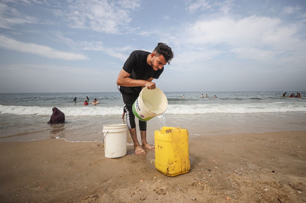 A Palestinian man fills empty bottles with sea water due to water crisis as a result of the suspension of water flow in the water pipes from Israel to the Gaza Strip in Deir al-Balah, Gaza on October 29, 2023.