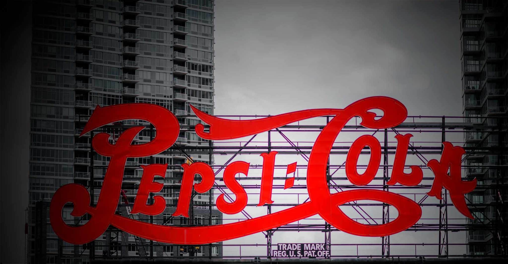 A neon sign of Pepsi-Cola logo set against skyscrapers in the background