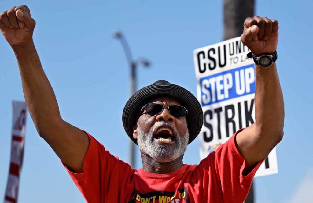 A man raises both fists and chants during an outdoor demonstration as a sign reading