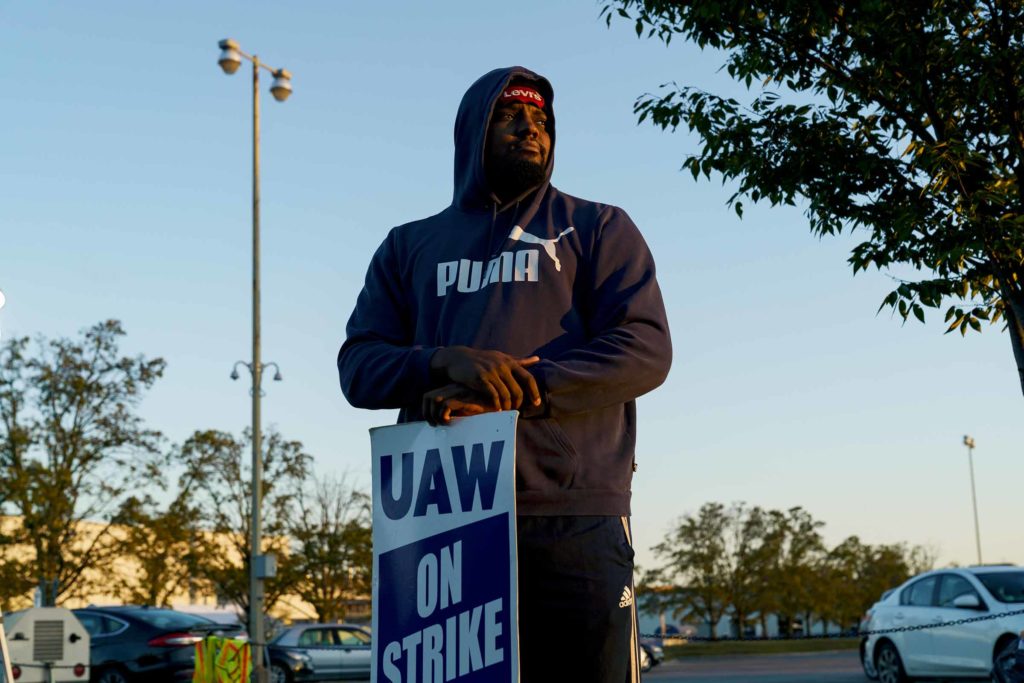 A man in a hoodie stands behind his