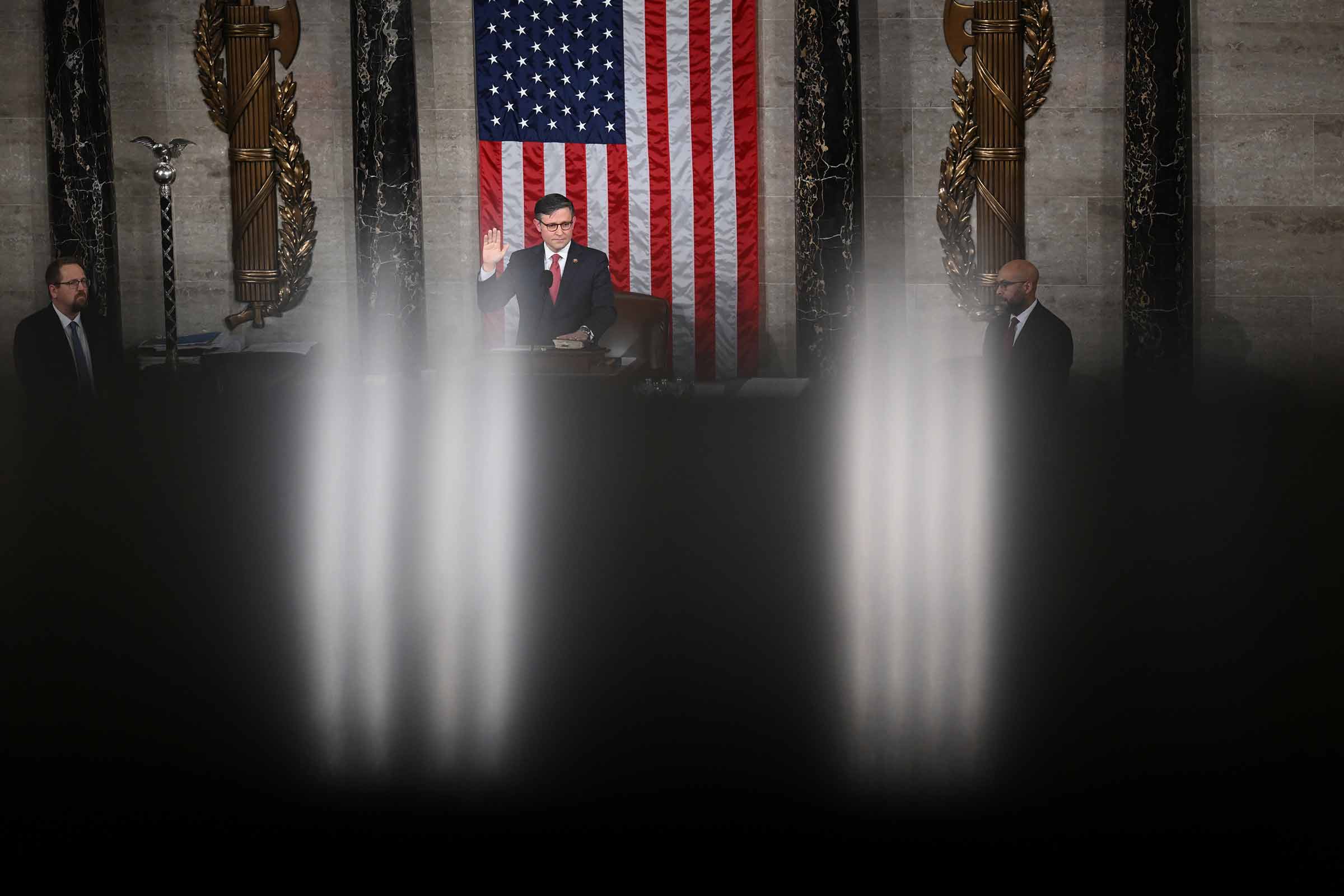 Mike Johnson stands in the u.s. house of representatives, between two fasces