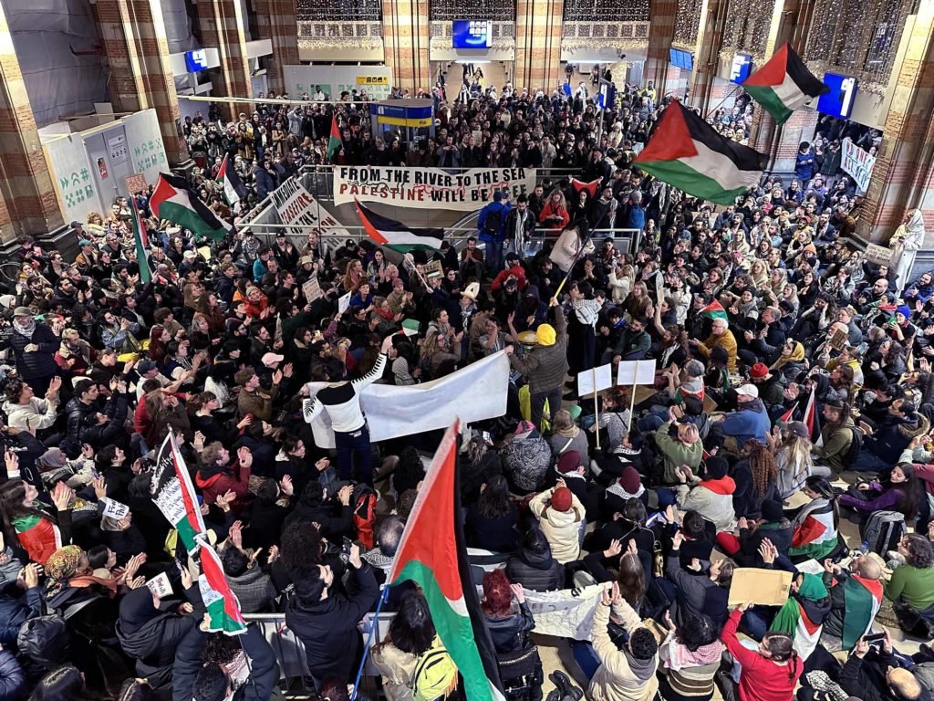 Hundreds of people waving the Palestinian flag and a banner reading