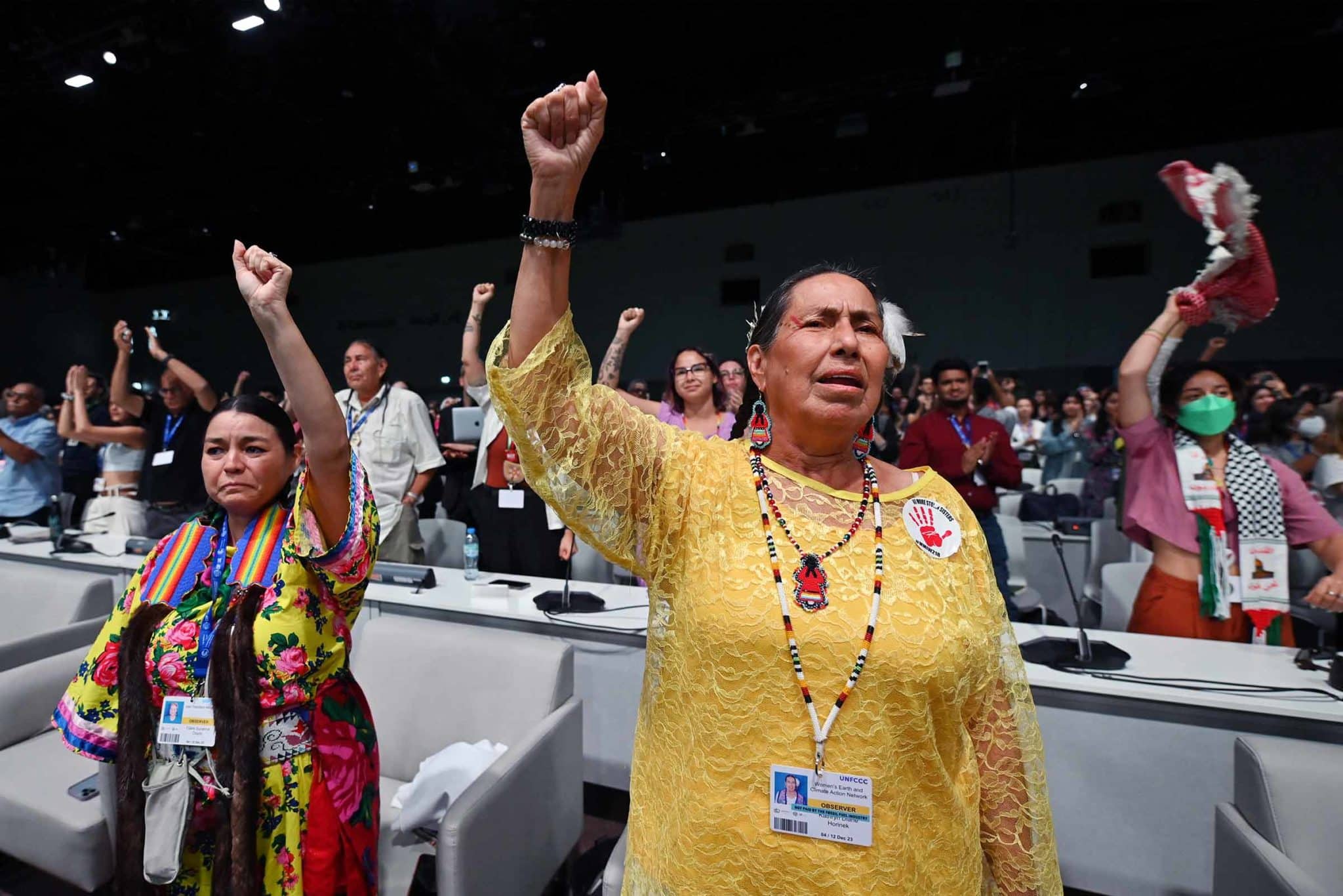 Indigenous people stand and raise their fists during COP28