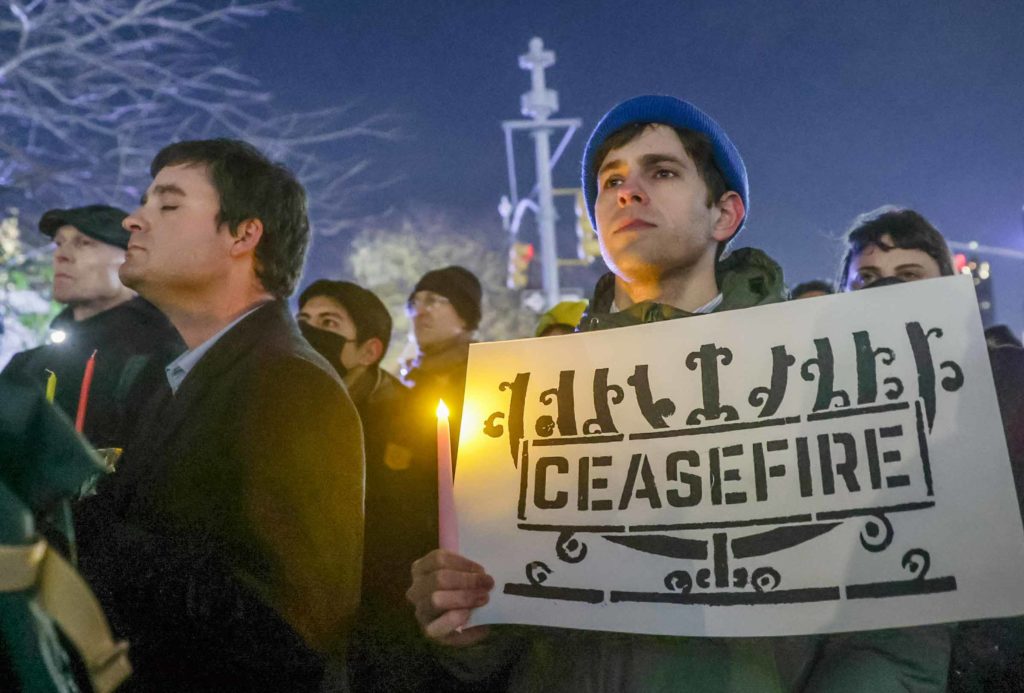 A man holds a sign with an image of a menorah with the word