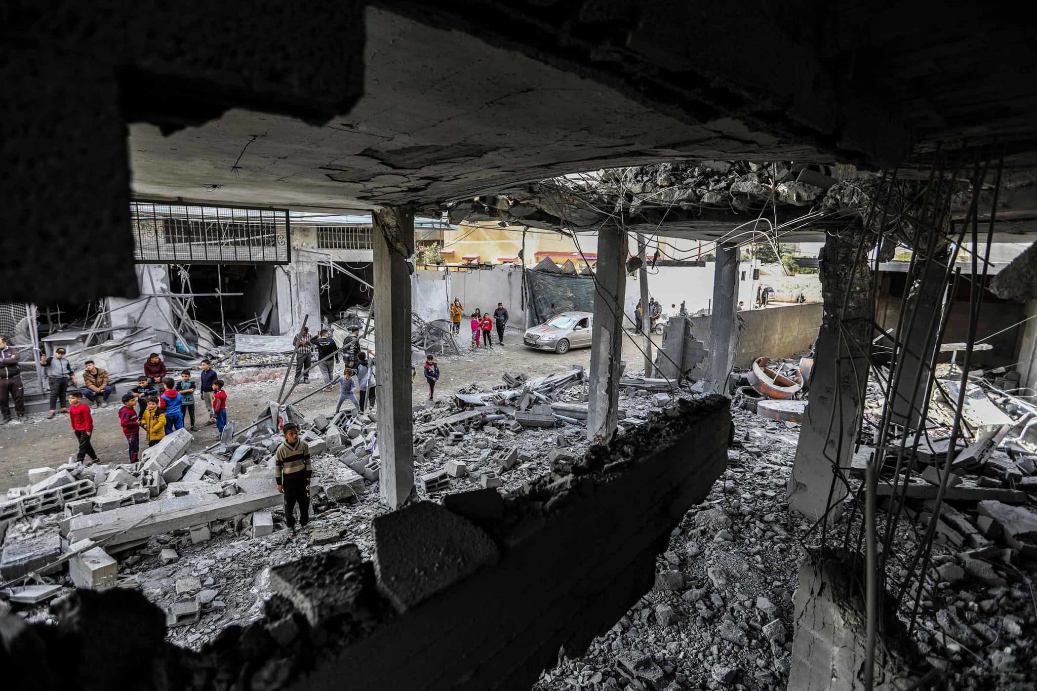 Palestinian children look up into a destroyed apartment building