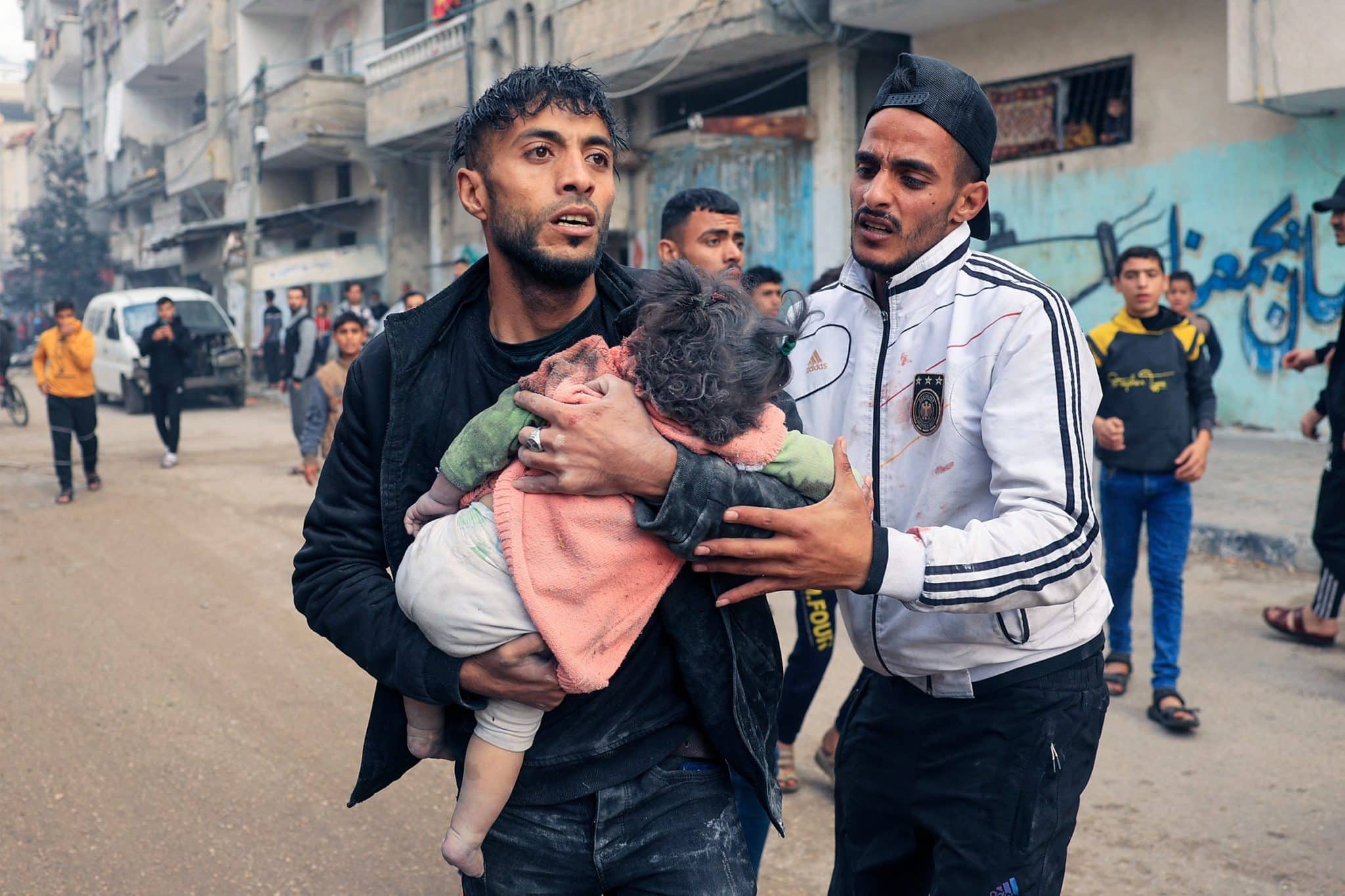 A man carries a child injured during Israeli bombardment in Rafah, in the southern Gaza Strip, on December 14, 2023.