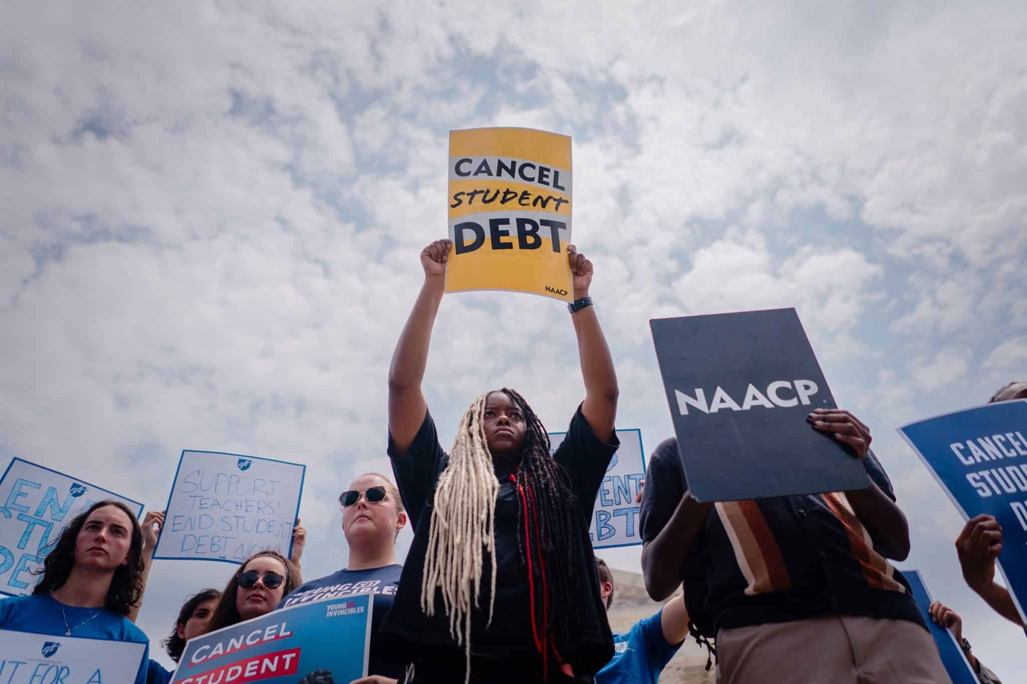 A Black woman holds a sign reading