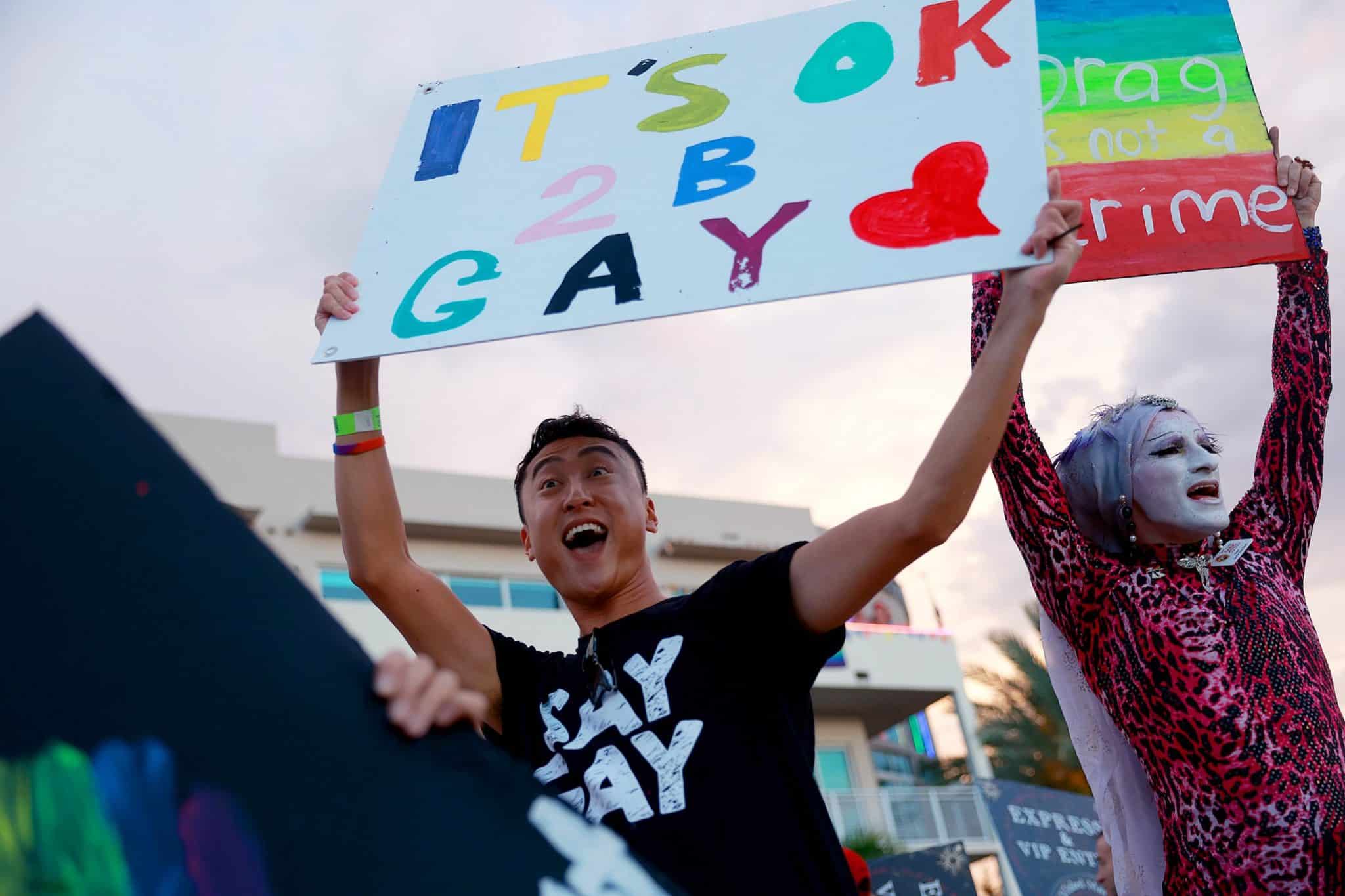 A jubliant person holds a sign reading "IT