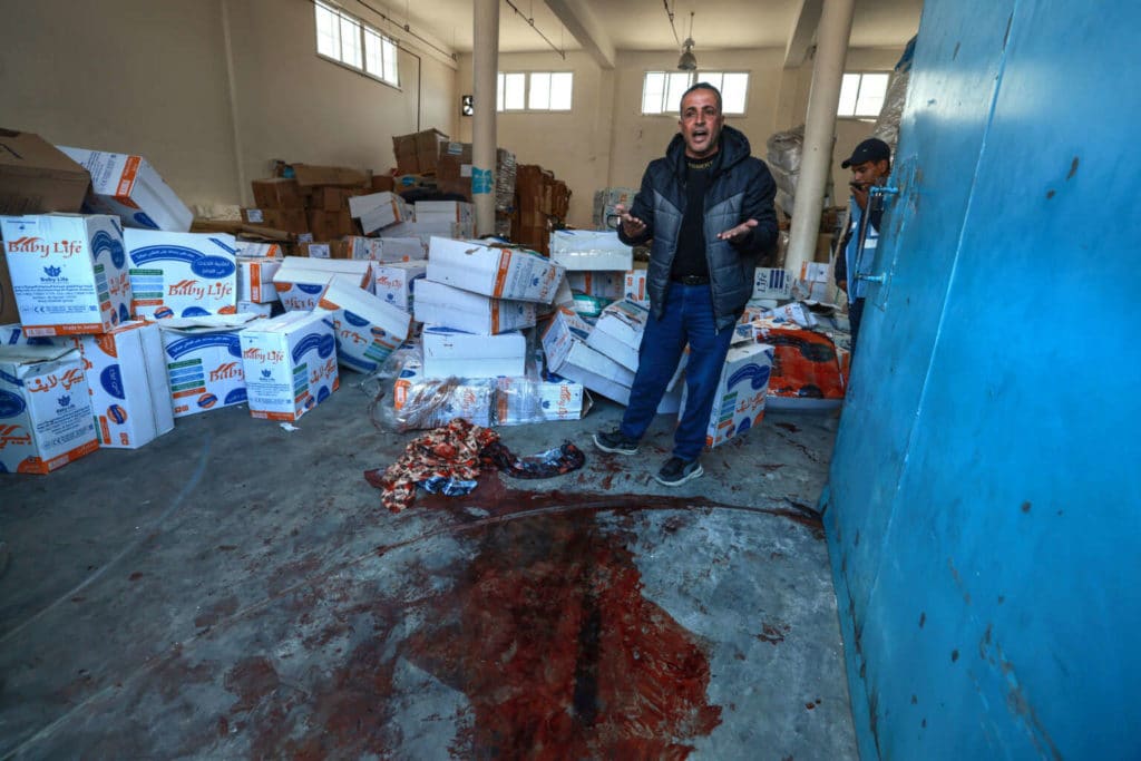 A man gestures near a pool of blood at an UNRWA warehouse and distribution centre in Rafah, in the southern Gaza Strip, following an Israeli strike on March 13, 2024.